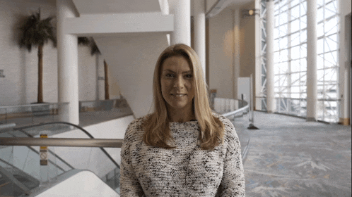 a woman in a sweater stands in front of a staircase