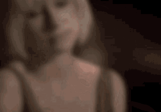 a blurry picture of a woman 's face and neck in a dark room .