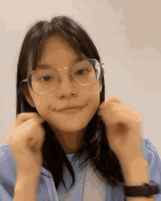 a young girl wearing glasses and a watch makes a funny face