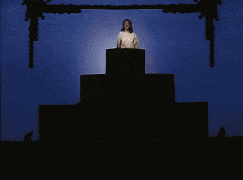 a woman stands on top of a large cake with candles
