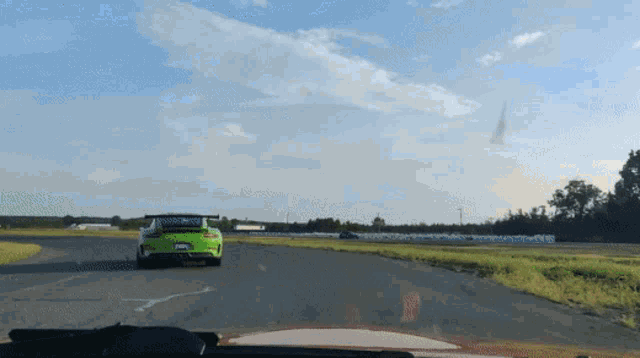 a green car is driving down a road with a license plate that says nc
