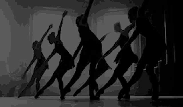 a group of ballerinas are dancing in a black and white photo .