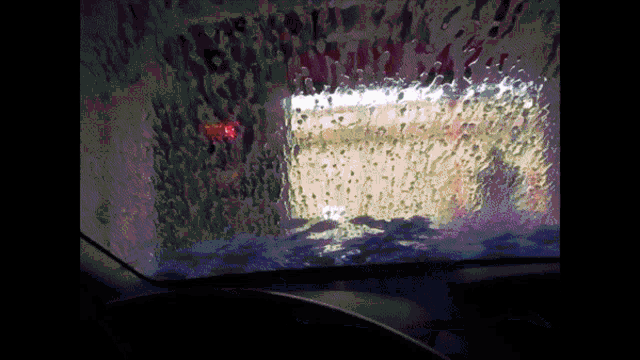 a car is going through a car wash with soap bubbles on the windshield