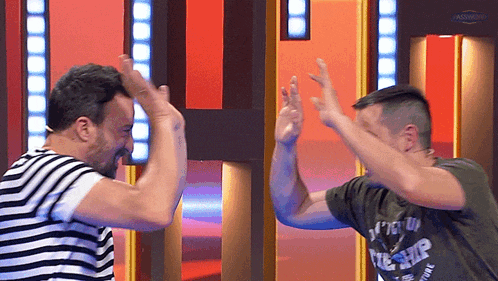 two men are giving each other a high five with one wearing a shirt that says ' the ship ' on it