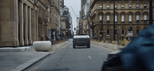 a car is driving down a city street with buildings in the background
