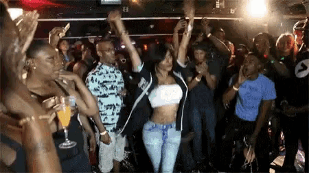 a woman in a crop top is dancing in front of a crowd