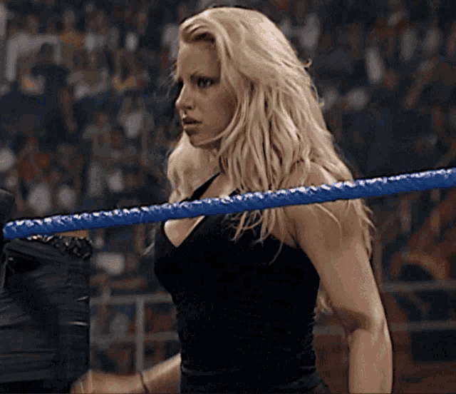a woman is standing in a wrestling ring with a blue rope