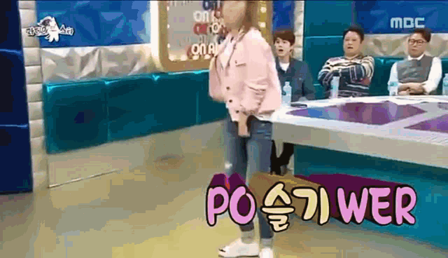 a woman in a pink jacket is standing in front of a table with the word power written on it .