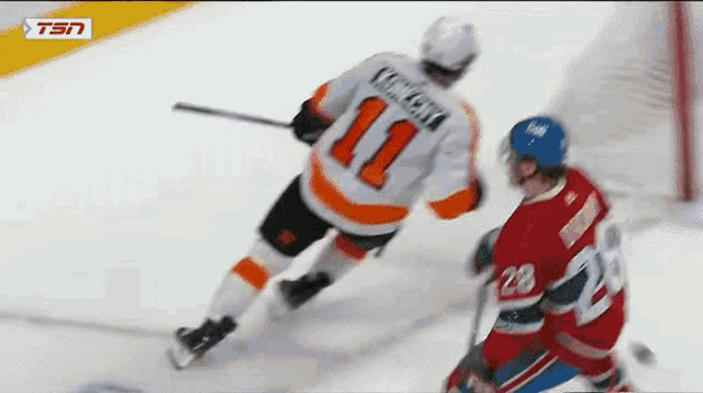 a hockey player with the number 11 on his jersey is being chased by another player