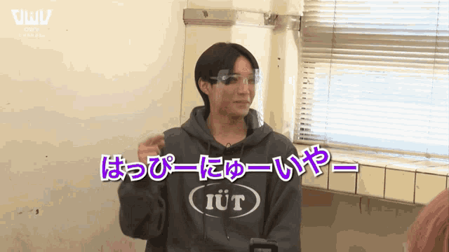 a man wearing a sweatshirt that says iut stands in front of a window