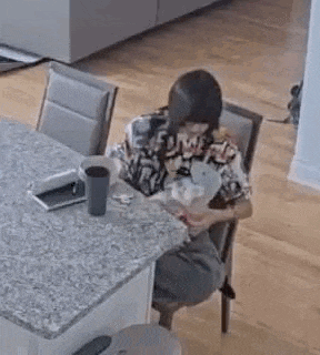 a woman is sitting at a table with a cup of coffee .