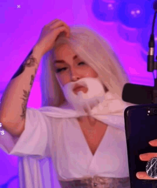 a woman with blonde hair and a white beard is taking a selfie with her phone .