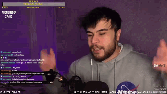 a man wearing a nasa sweatshirt is talking into a microphone