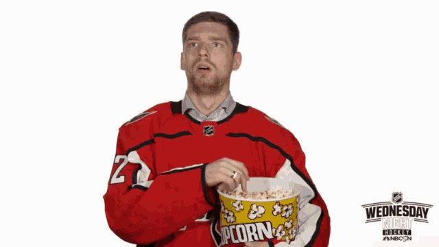 a man in a red jersey with the number 1 on it is holding a bucket of popcorn
