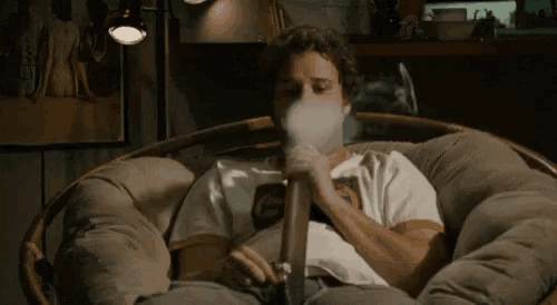 a man is sitting in a wicker chair smoking a pipe .