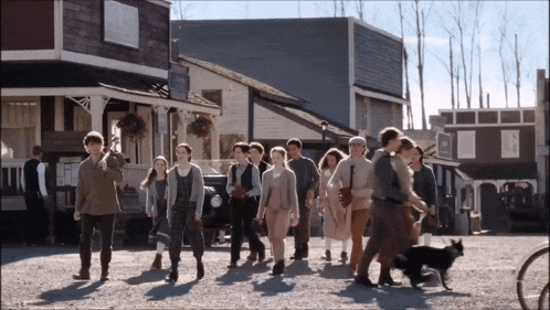 a group of people are walking down a street in front of a building that has a sign on it that says ' a '