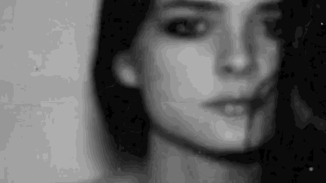 a black and white photo of a woman 's face with her mouth open .