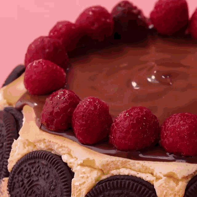 a cheesecake with oreos and raspberries on top of it
