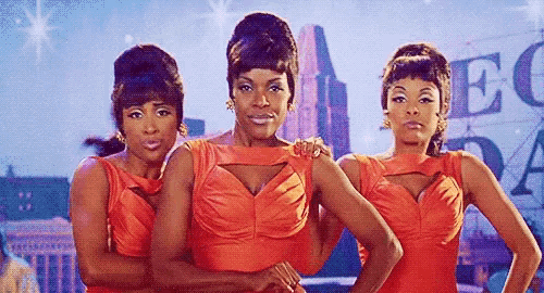 a group of three women in red dresses are standing next to each other .