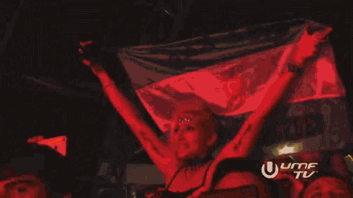 a woman holds up a green and yellow flag with the letters u and m on the bottom