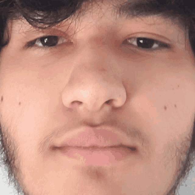 a close up of a man 's face with a beard and black eyes
