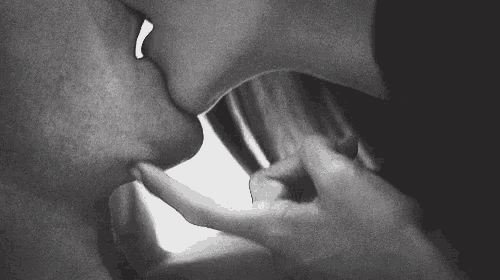 a black and white photo of a man and woman kissing each other .