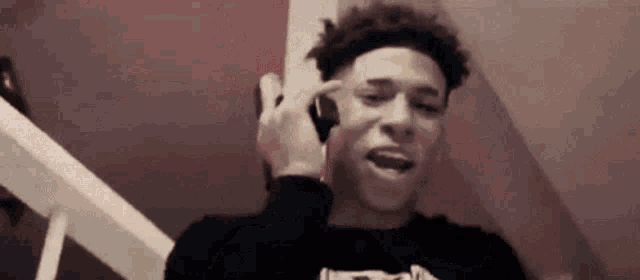 a young man is talking on a cell phone while sitting on stairs .
