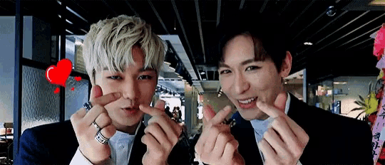 two men are making a heart shape with their hands .