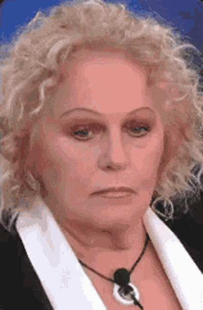 a close up of a woman 's face with curly hair and a necklace .