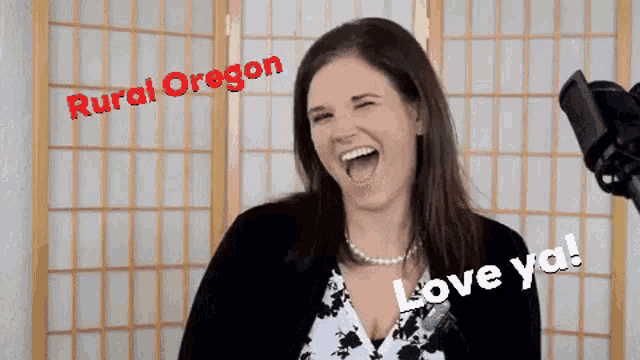 a woman is laughing in front of a microphone with rural oregon written on the top
