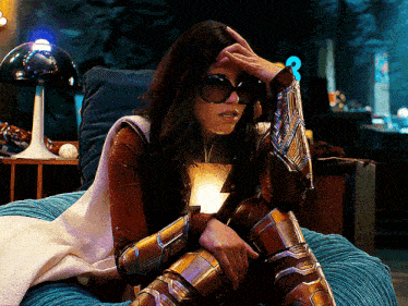 a woman in a superhero costume is sitting in a chair with her hand on her head