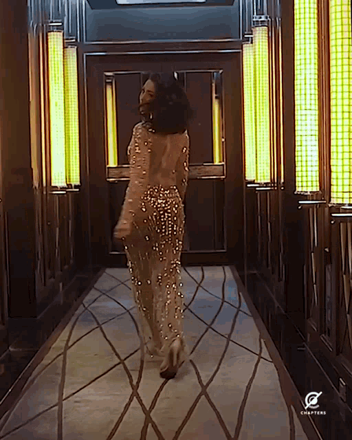 a woman in a dress is walking down a hallway with a chapters logo on the wall