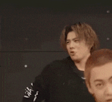 a man in a black hoodie is making a funny face while standing next to another man .