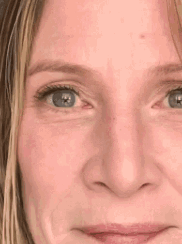 a close up of a woman 's face with blue eyes and a red eye