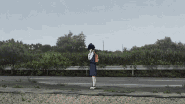 a person standing on the side of a road with a backpack