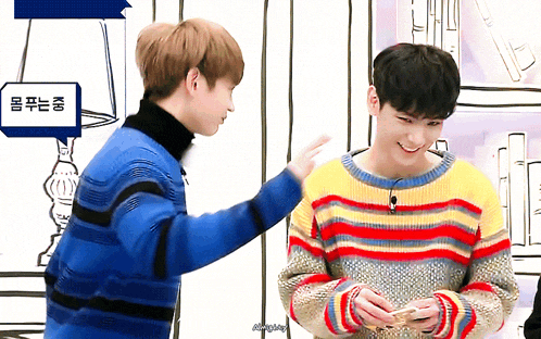 two young men are standing next to each other and one of them is wearing a colorful striped sweater