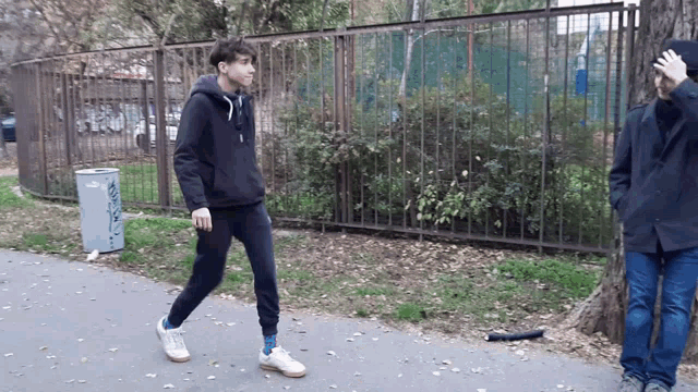 a man walking down a sidewalk next to a trash can that says ' a ' on the side