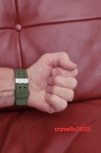 a man 's wrist with a green watch and the year 2025 on it