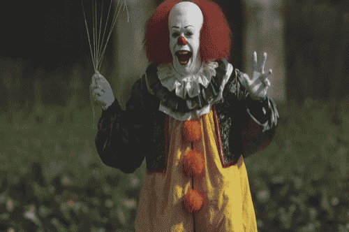 a clown holding a balloon and giving a thumbs up