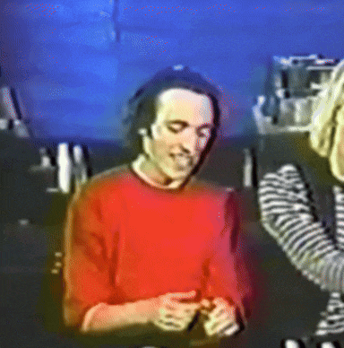 a man in a red sweater is talking to a woman in a striped shirt