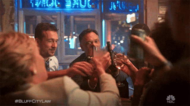 a group of people toasting at a bar with the nbc logo in the corner