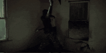 a person is hanging from a rope in a dark room with a bag on their back .