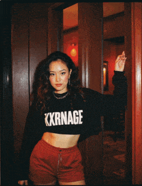 a woman wearing a black crop top with kxrnage on it