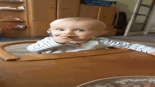 a baby is sitting at a table with a plate on it and a sign that says ' dont be a kid '