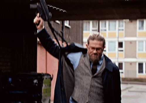 a man with a beard is holding up a gun