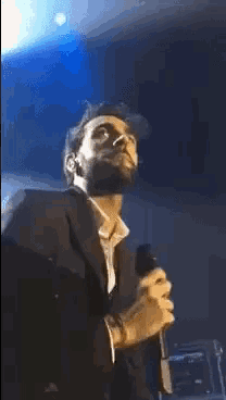a man in a suit is singing into a microphone on stage