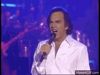 a man in a white shirt singing into a microphone