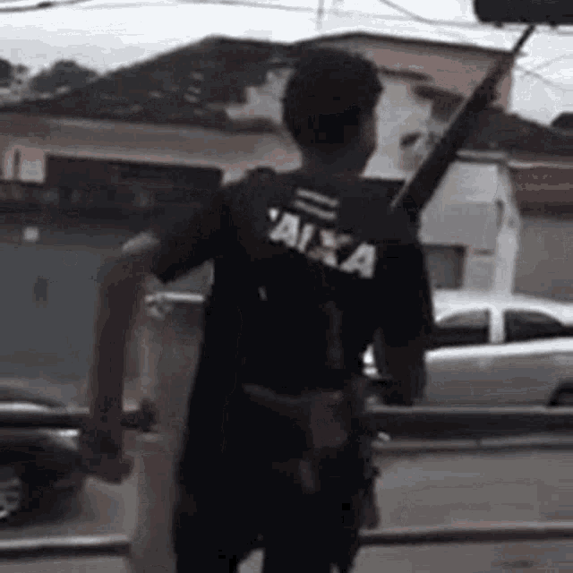a man is holding a gun in his hand and wearing a black shirt with the word caixa on it .