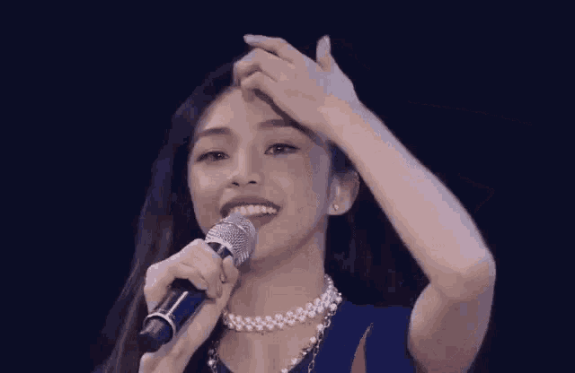 a woman is holding a microphone and smiling .