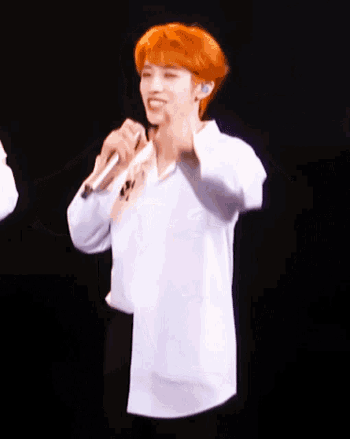 a man with red hair is singing into a microphone on a stage
